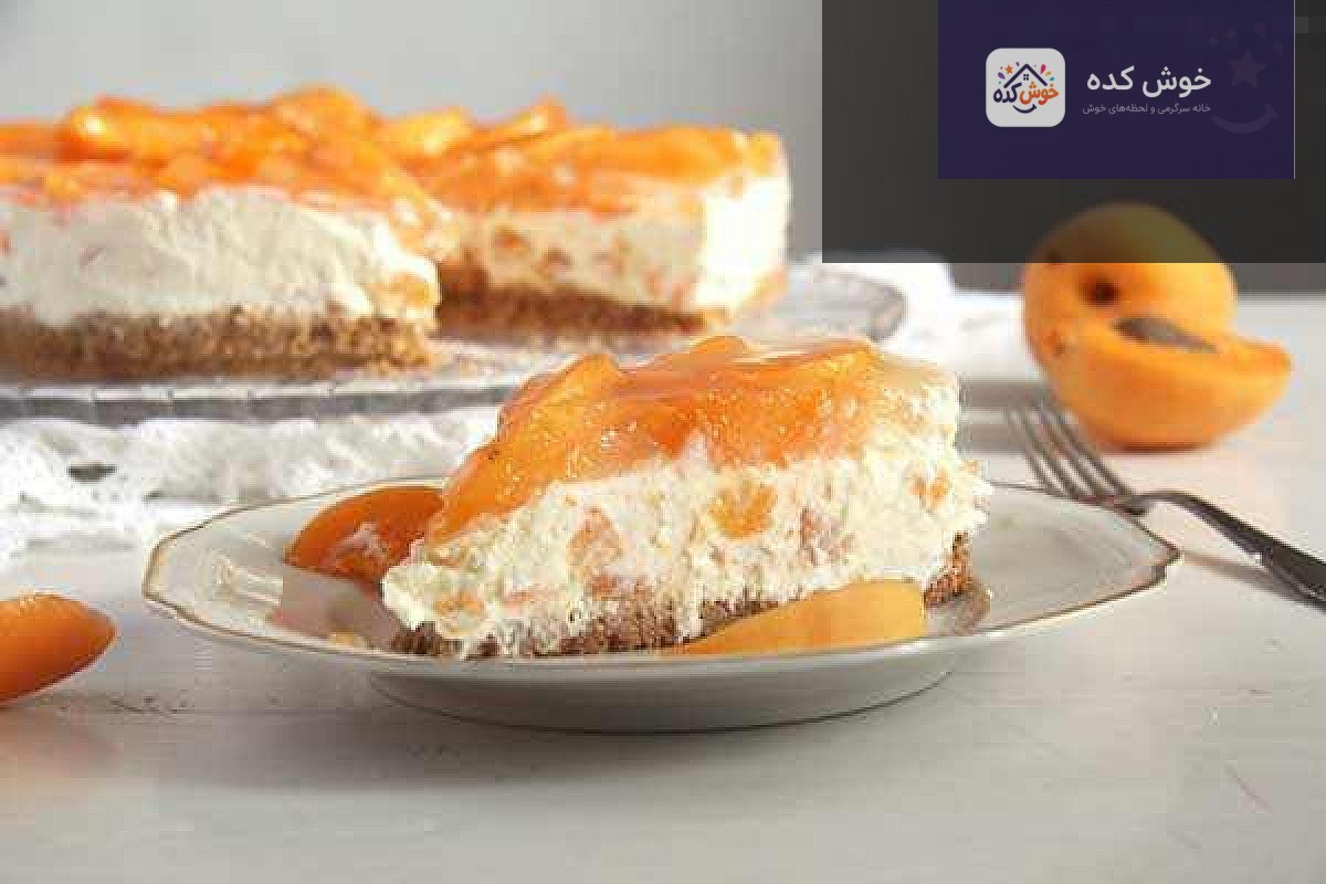 چیز کیک زردآلو با لایه های کرم پنیری و بیسکویتی، تزئین شده با برش های زردآلوی تازه و نعناع