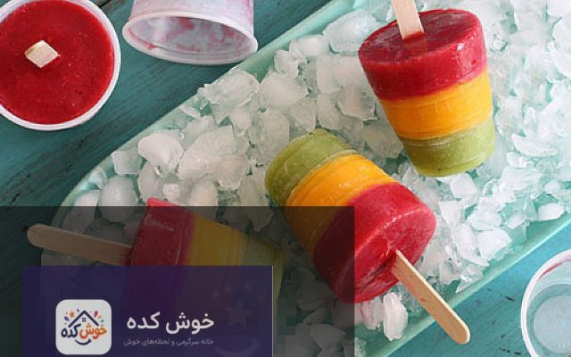 بستنی یخی سه رنگ میوه ای در لیوان های شیشه ای، آماده سرو، با لایه های توت فرنگی، انبه و کیوی