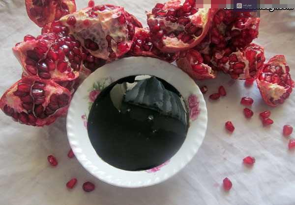 آب انار طبیعی و تازه در حال جوشیدن در قابلمه روی اجاق گاز برای غلیظ شدن و تبدیل به رب انار