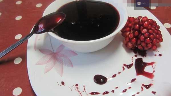 رب انار خانگی غلیظ و تیره رنگ در حال پخت نهایی در قابلمه، با بافتی یکدست و براق