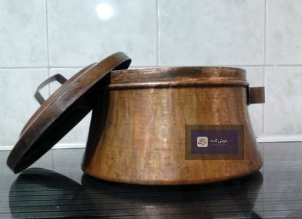 رب گوجه فرنگی در حال غلیظ شدن در یک دیگ مسی سنتی، نشان‌دهنده پخت با کیفیت و اصیل.