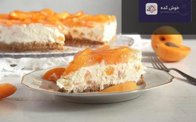 چیز کیک زردآلو با لایه های کرم پنیری و بیسکویتی، تزئین شده با برش های زردآلوی تازه و نعناع