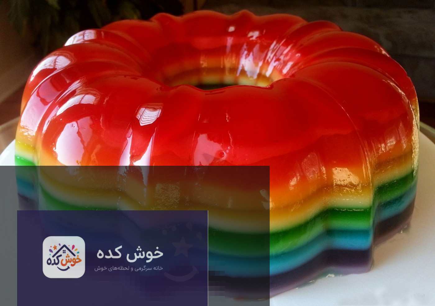 ژله رنگین کمان لایه ای در لیوان، با لایه های رنگارنگ و میوه های تازه تزئین شده، آماده سرو.