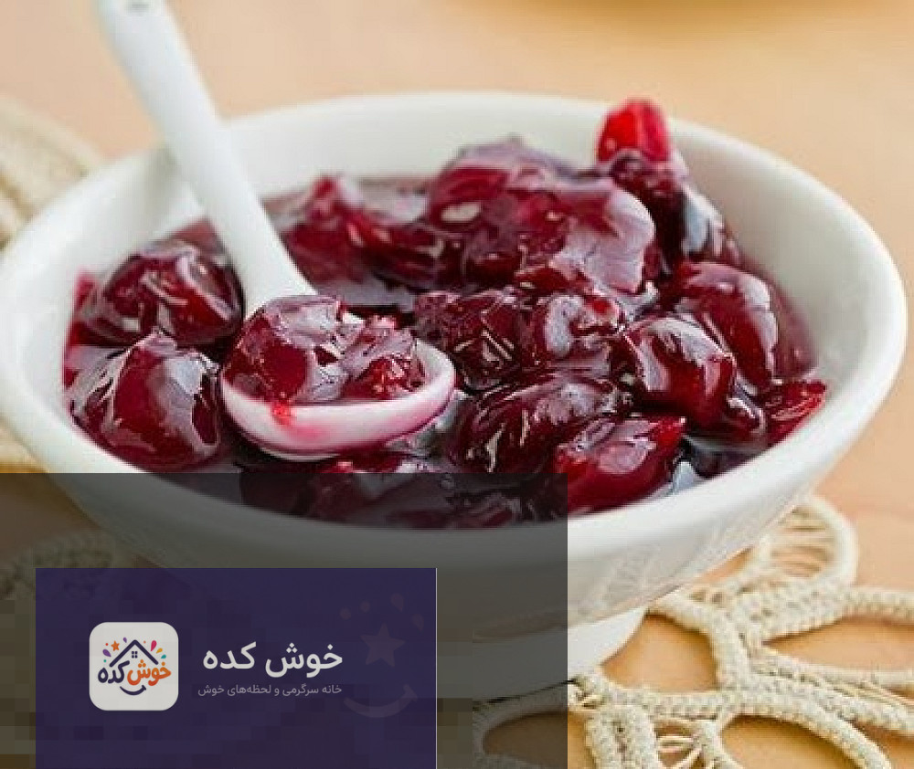 پخت مربای آلبالو مربای آلبالوی خوشرنگ در حال پخت در قابلمه، با قاشق چوبی برای هم زدن