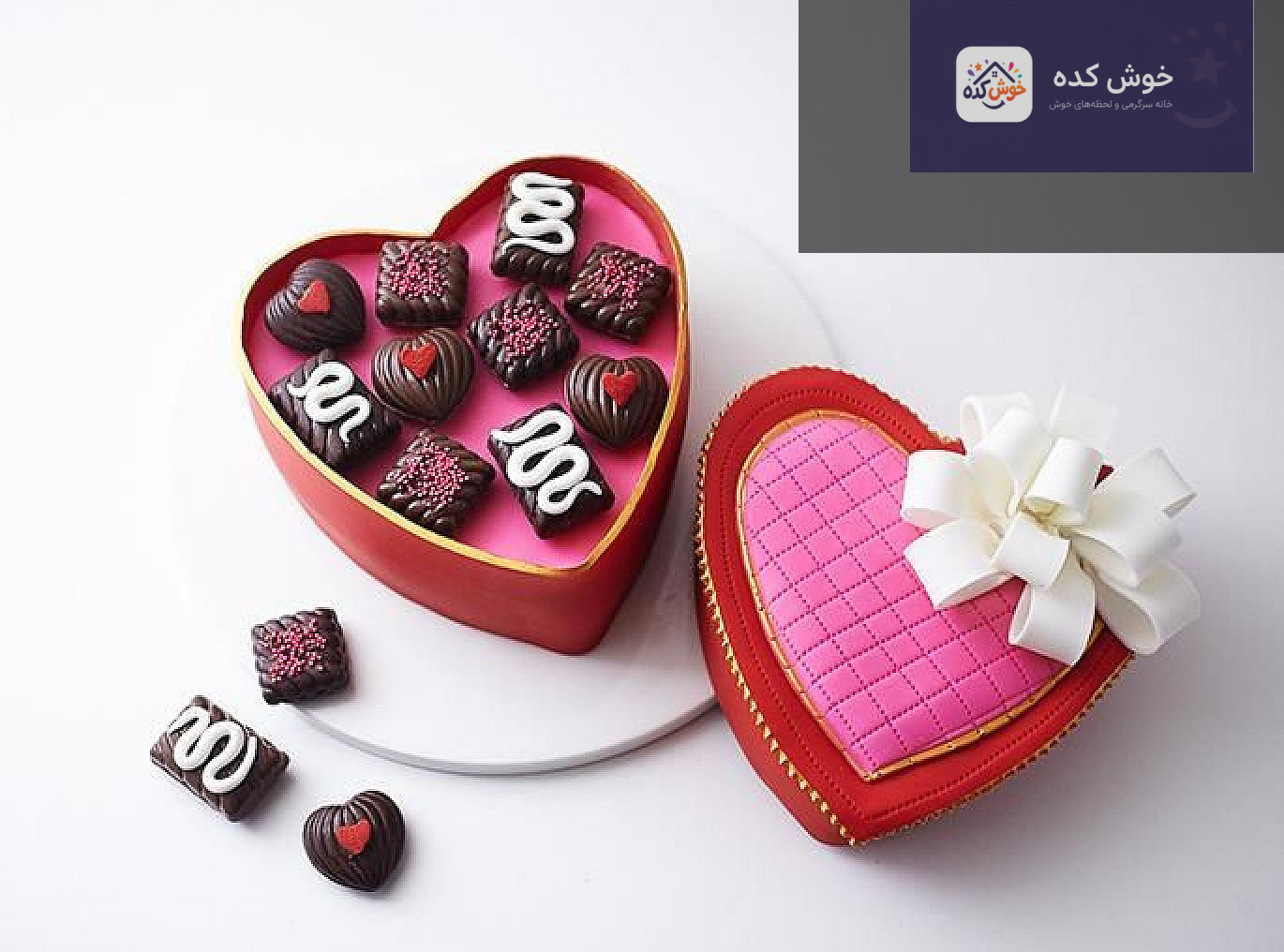 کیک تولد تزیین شده به شکل جعبه شکلات با روبان قرمز و گل‌های کوچک خوراکی