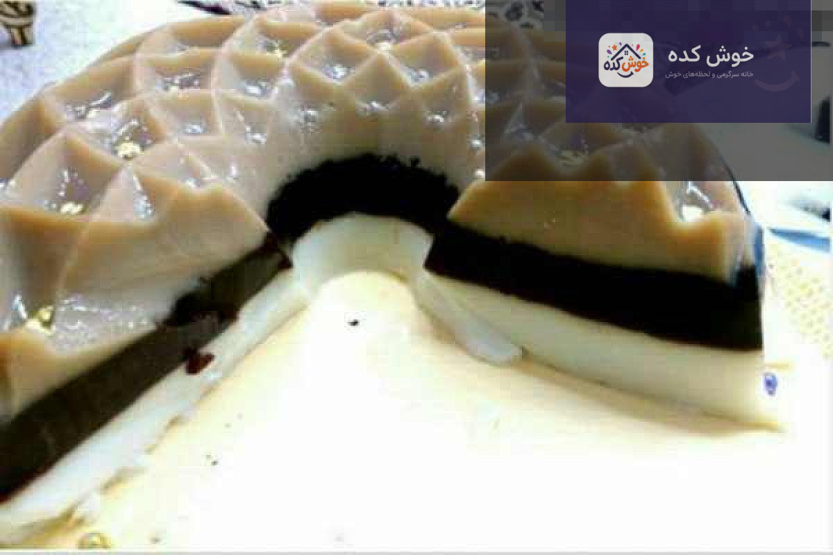 مواد اولیه ژله شکلاتی سه رنگ مواد لازم برای تهیه ژله شکلاتی سه رنگ شامل پودر ژله، شیر، شکر، خامه و شکلات تختهای روی میز چوبی