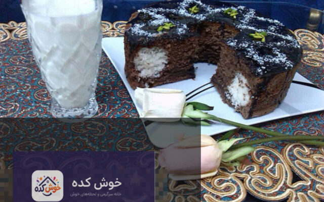 کیک سورپرایز نارگیلی برش خورده با لایه های سفید و مغز نارگیل، تزیین شده با پودر نارگیل و گلبرگ های خوراکی