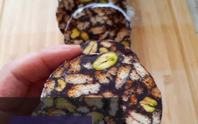 شیرینی یخچالی شکلات آلمانی با تزیین پودر نارگیل و خلال پسته، آماده سرو در ظرف سفید